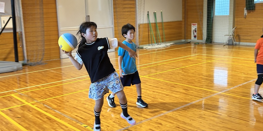 体育館でボールを投げる小学生